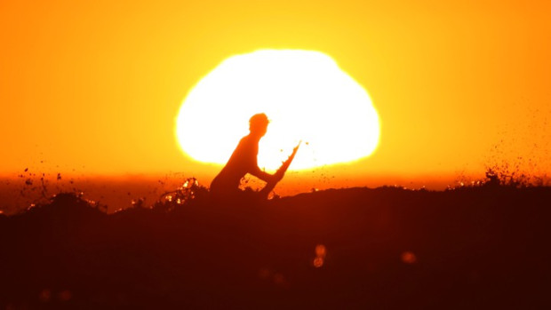 A surfer pulls off a wave as the sun sets in Cardiff during what local media reported to be a record breaking heat wave in Southern California