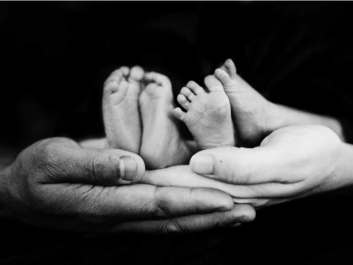 Hands cradling the feet of two infants